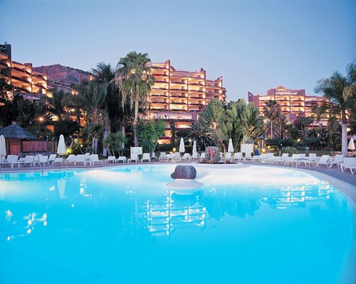 Фотография курортного бассейна с шезлонгами и видом на курорт